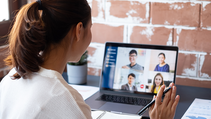 woman waving at colleagues on his laptop