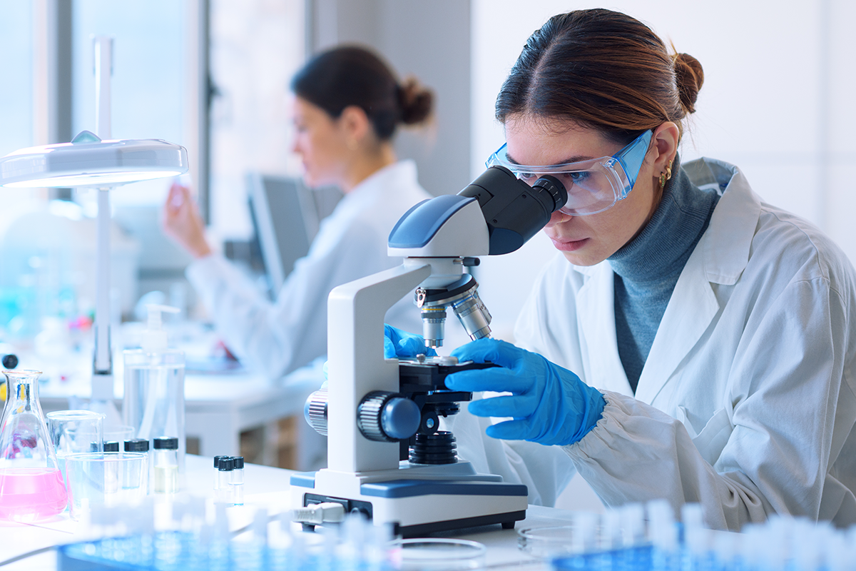 scientist looking through microscope