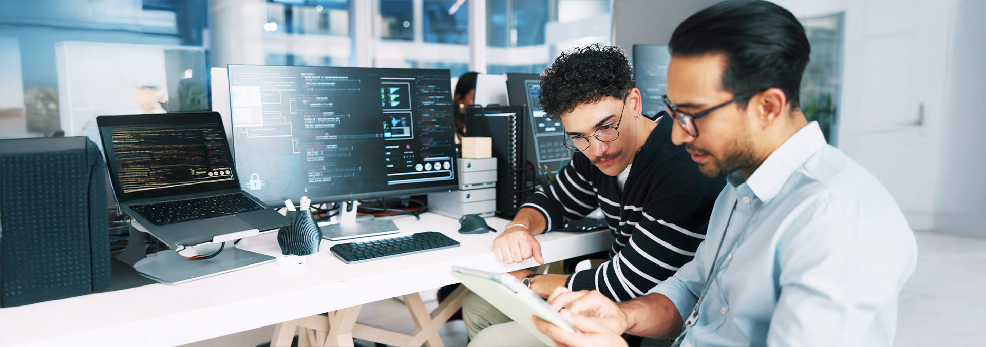 Two individuals discussing notes at a desk