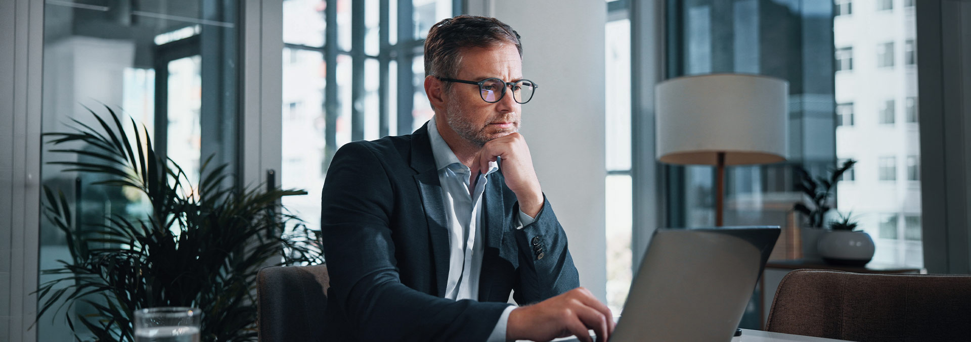 Suited officer worker looking pensively at laptop screen