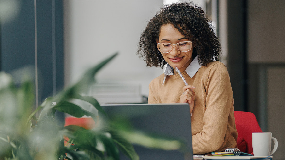 Woman at her desk looking over the laptop on a screen