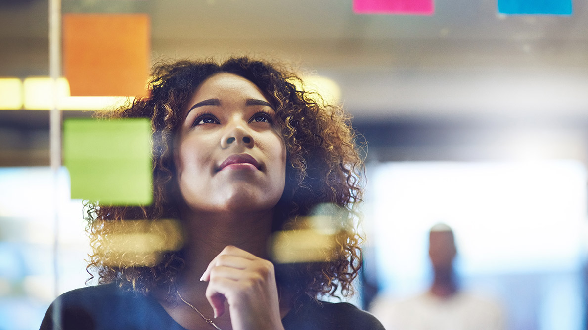 Woman looking at post it notes on a transparent board