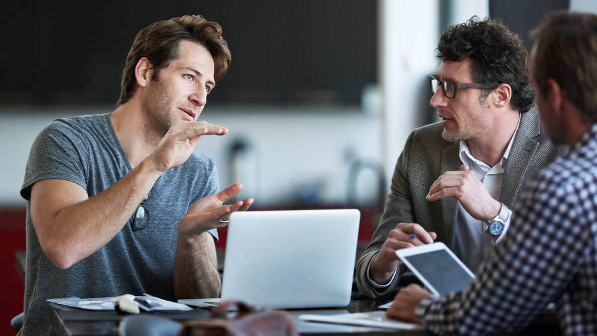 Three individuals in an office discussing a topic