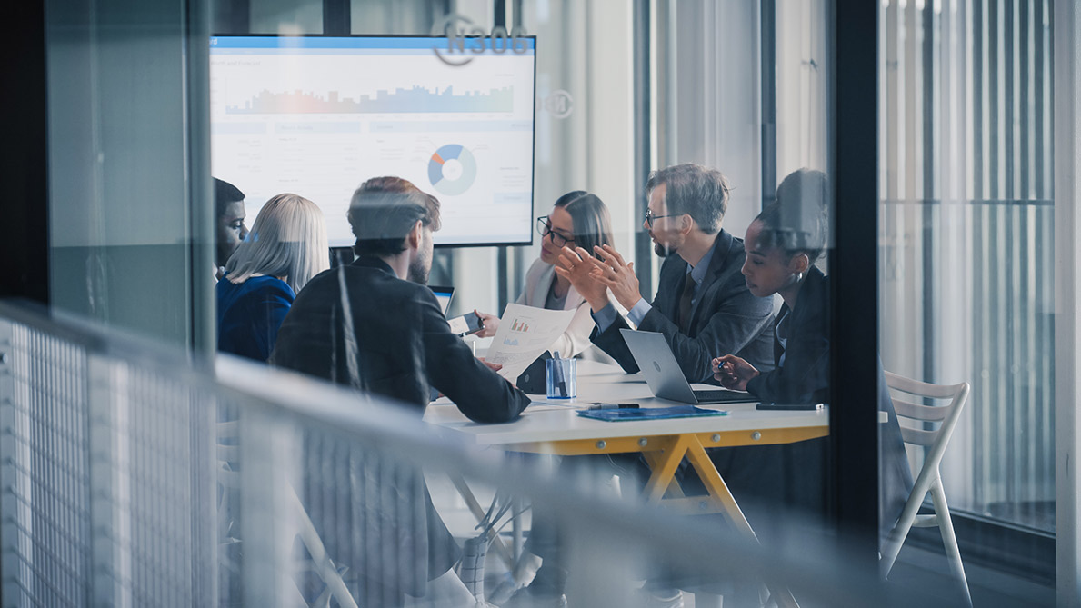 Individuals in a boardroom looking at a powerpoint of learning data
